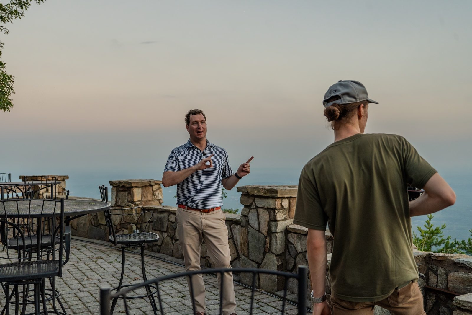 Damian Hall on a fence rail directing an evening shoot at 105 The Cliffs Parkway, mountains and sunset behind him